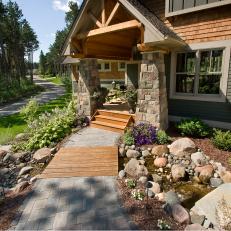 Enchanting Entry With Wood Footbridge, Paver Walkway and Stream