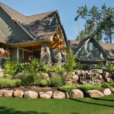 Decorative Front Yard Landscaping Featuring Large Rocks, A Waterfall Feature and Bright Plant Life