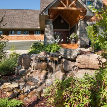 Front Yard Waterfall With Boulder Landscape Shaping and Surrounding Garden 