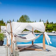 Luxurious Poolside Four-Post Hammock With White Sheet and Striped Pillows