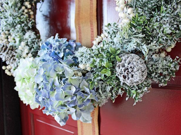 Add faux greenery, flowers, berry sprigs and glittered pinecones to a grapevine wreath then cover with faux snow to give your front door a cheery update during winter months.