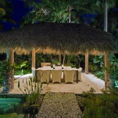 Tropical Dining Area at Night with Hut, Water Feature and Coral Stone