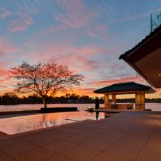 Neutral Tile Patio Surrounds Negative Edge Swimming Pool in Lakeside Backyard Design 