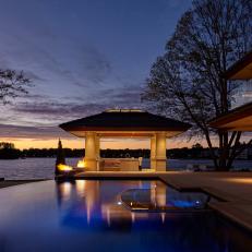 Sunset View of Lakeside Backyard Featuring Modern Swimming Pool With Negative Edge and In-Water Lighting 