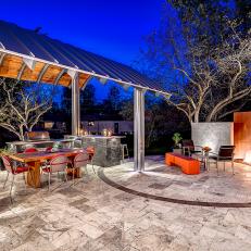 Outdoor Living Space with Kitchen and Fireplace at Night