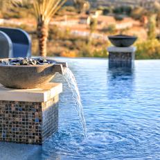 Close Up on In-Pool Column With Waterfall Bowl, Black Pebbles and Iridescent Tile Exterior