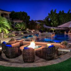 Stone Tile Fire Pit Patio Above Luxurious Swimming Pool and Tropical Landscaped Yard 