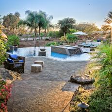 Tropical Plants Bordering Stone Walkway Leading to Luxurious Backyard Swimming Pool Landscaping 