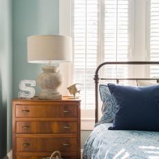 Blue Bedroom With Iron Bed, Dresser, White Lamp and Blinds