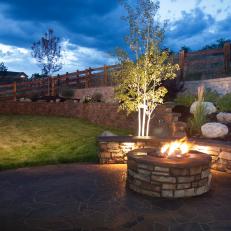 A Fire Pit Adds Dramatic Color and Warmth to a Backyard's Stone Wall Landscape