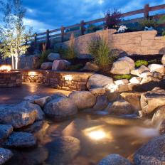 Sloping Stone Backyard Walls Accent A Fire Pit and Water Feature