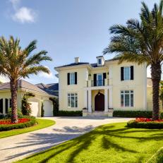 Classy, Traditional Home Exterior With Flower Bed Palm Trees and Light Brick Driveway 