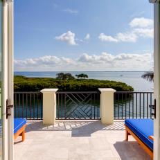 Relaxing Balcony With Water View From Bright Blue Cushioned Lounge Chairs 