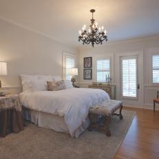 Traditional Bedroom With Tableclothed Nightstands, Plush White Bedding and Chandelier 
