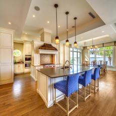 Open Transitional Kitchen Featuring Bright Blue Bar Chairs and Copper Covered Range Hood 
