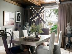 This wow-worthy dining room has a transitional style and moody European look, with curated art on dark walls and a dramatic chandelier.