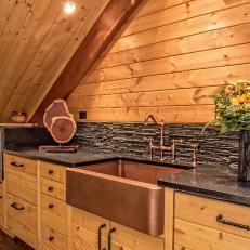 Natural Wood Loft Kitchen With Copper Farmhouse Sink, Textured Tile Backsplash and Dark Countertop 