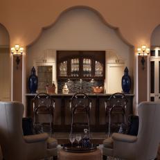 Low Light, Cozy Bar and Lounge With Glass Storage Cabinets Over Tile Bar Backsplash and Gray Leather Armchairs 