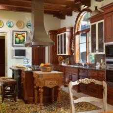 French Country Kitchen With Wood Cabinetry, Exposed Beams and Colorful Tile "Rug" Below Eat-In Island 