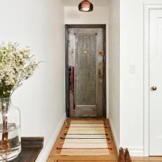Colorful Tasseled Foyer Rug Leading to Distressed, Gray Front Door 