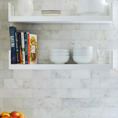 Kitchen Details Featuring Floating White Shelves Over White Marble Tile Wall 