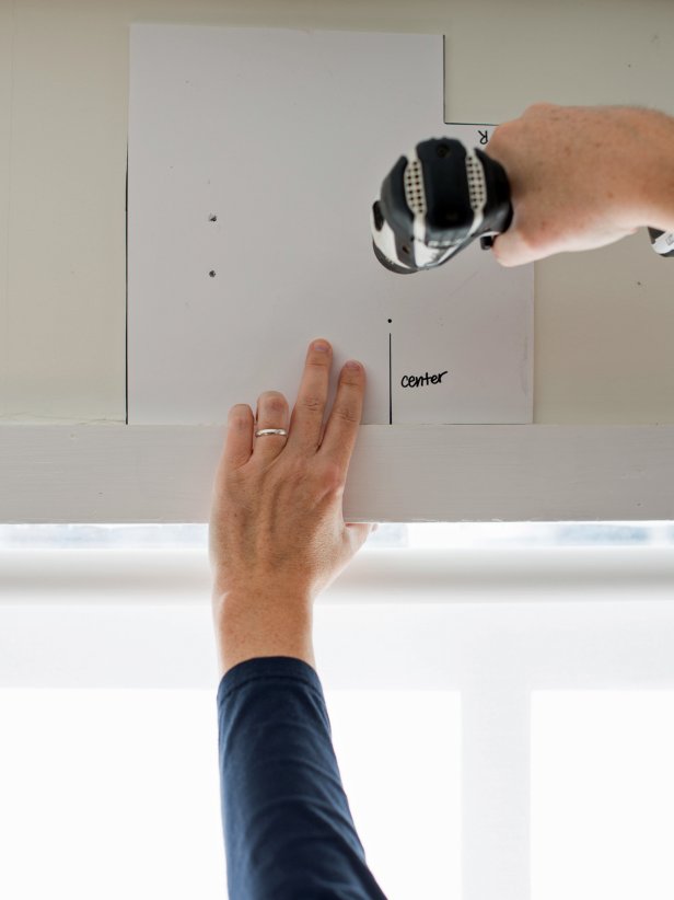 Place template on window trim (either top, left, or right) and drill through marks.  Install curtain brackets in drilled holes, either with wall anchors or directly into the wall material.  Tip: For windows without wood trim, temporarily tack up a level wooden board to use as a guide and remove once holes are drilled.