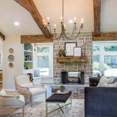 Open Concept Living Room With Gray Stone Fireplace and Exposed Beam Vaulted Ceilings