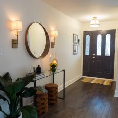 Dark Front Door, Glass Wall Table and Square Lamp Shade Sconces Over Hardwood Floor Entryway 