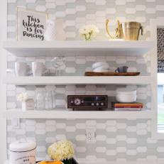 Kitchen Floating Shelf Decor Featuring Personal Touches and Dish Storage Over Hexagonal Gray and White Wall Tile 