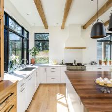 Wood Accent Details in Bright Contemporary Kitchen With Large Island and Statement Pendant Lights 