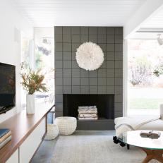 Global-Chic White Living Room Featuring Textured Fireplace Surround and Walnut Media Cabinet