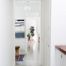 Hallway View of Polished Concrete Flooring, Globe Pendant Lights and Bright, White Home Design 