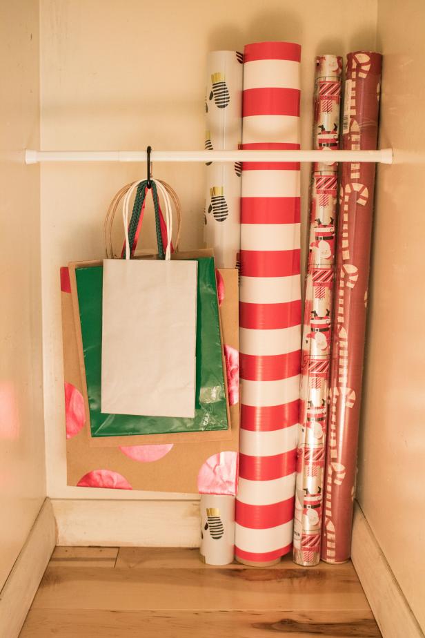 A tension rod holds wrapping paper in place in a closet.