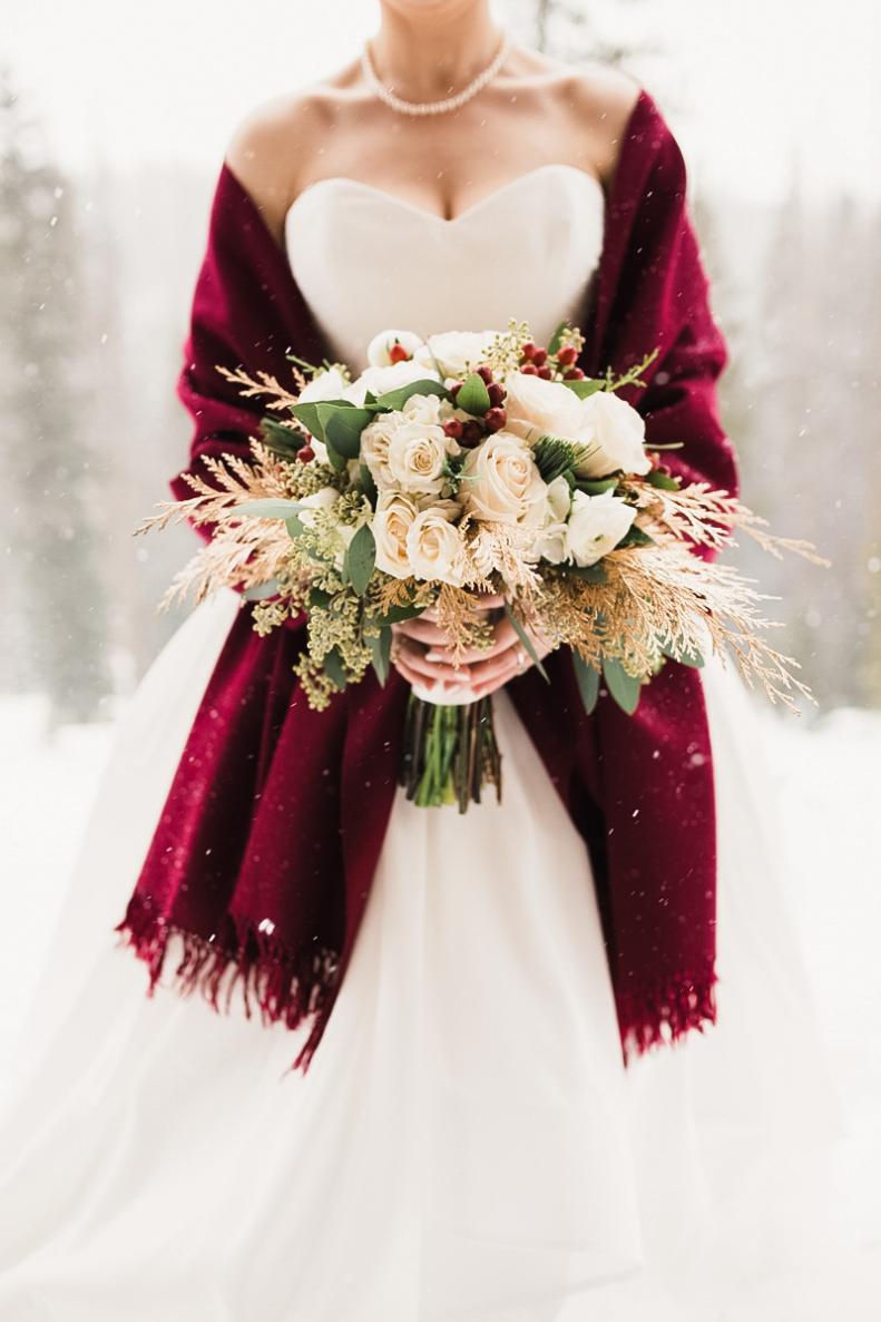 This winter bouquet features a breathtaking combination of cream roses, red hypericum berries, seeded eucalyptus and spray-painted gold cypress greenery. Photo: Greenhouse Creative Studios