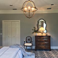 Unique Metal Chandelier Over Blue Bed Linens and Patterned Carpet in Traditional Bedroom