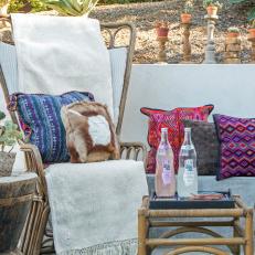 Concrete Patio With Wicker Furniture and Colorful, Patterned Throw Pillows