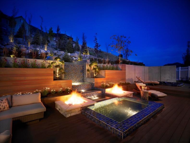 Landscaping Overlooks Modern Deck With Water Feature and Fire Pits