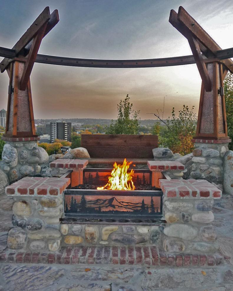 Wood Bench Behind Fire Pit Under Stone and Metal Structure