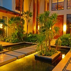 Romantic Asian Front Door Entryway With Concrete Stepping Stone Walkway Over Pond and Palm Trees