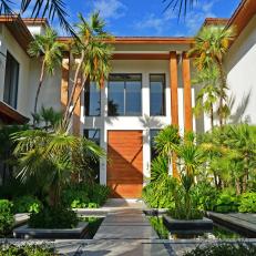 Bright, Asian Style Wood Front Door With Matching Columns and White Home Exterior and Tropical Palm Garden  