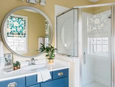Crisp white subway tile mixed with bold blue cabinetry and an oversized walk-in shower give this guest bathroom an inviting aesthetic.