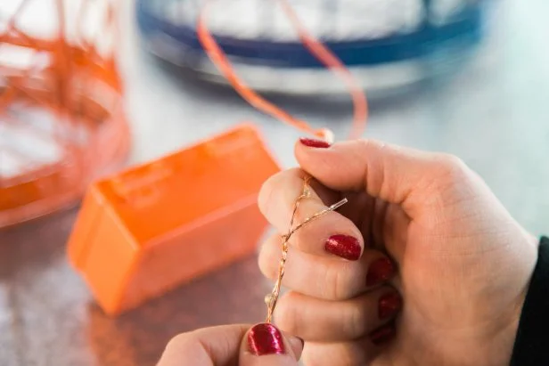 Once the battery pack is dry to the touch, you’re ready to place the lights in the birdcage. If your lights are super long, fold the string back on itself and twist the loose ends together to half the string which will save time on the weaving process. To start, place the battery pack in the bottom of the cage, then pull the end of the light string all the way through the top of the cage and begin weaving.