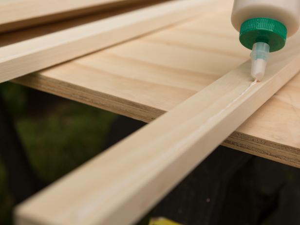 To trim out the bar top, take each piece of 1x2 and add a generous bead of wood glue, then secure it to the edge of the 1x10 bar top with hammer and nails or a nail gun if you have one, making sure everything is flush. Repeat until all four sides are complete. We suggest reinforcing the back 1x2 trim piece with a several wood screws for strength.
