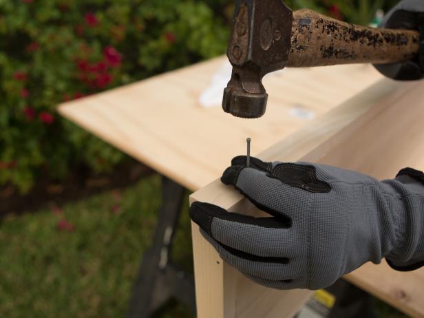 To trim out the bar top, take each piece of 1x2 and add a generous bead of wood glue, then secure it to the edge of the 1x10 bar top with hammer and nails or a nail gun if you have one, making sure everything is flush. Repeat until all four sides are complete. We suggest reinforcing the back 1x2 trim piece with a several wood screws for strength.