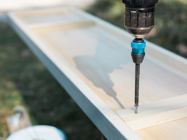 Next, attach the three 10 inch bracing 1x2s to the underside of the bar top, using 2-inch wood screws. Position two about 12 inches from the outside edges and finish with one brace in the middle. Make sure you leave enough room for your ice bucket hole!