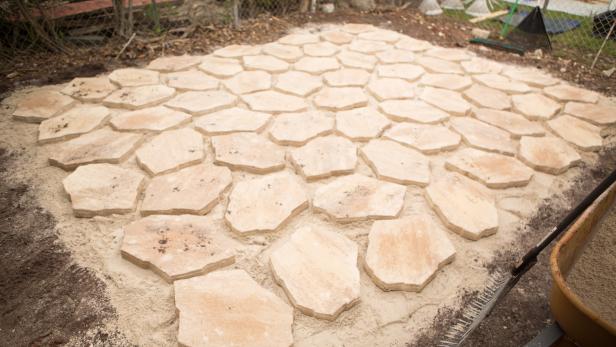 Continue placing pavers, checking that they’re level as you work and leaving somewhat uniform gaps between the stones. As you get close to the perimeter, choose smaller stones and turn appropriately so you don’t overstep the patio’s border