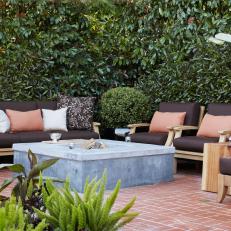 Outdoor Seating Area Around Square Fire Pit With Greenery Backdrop