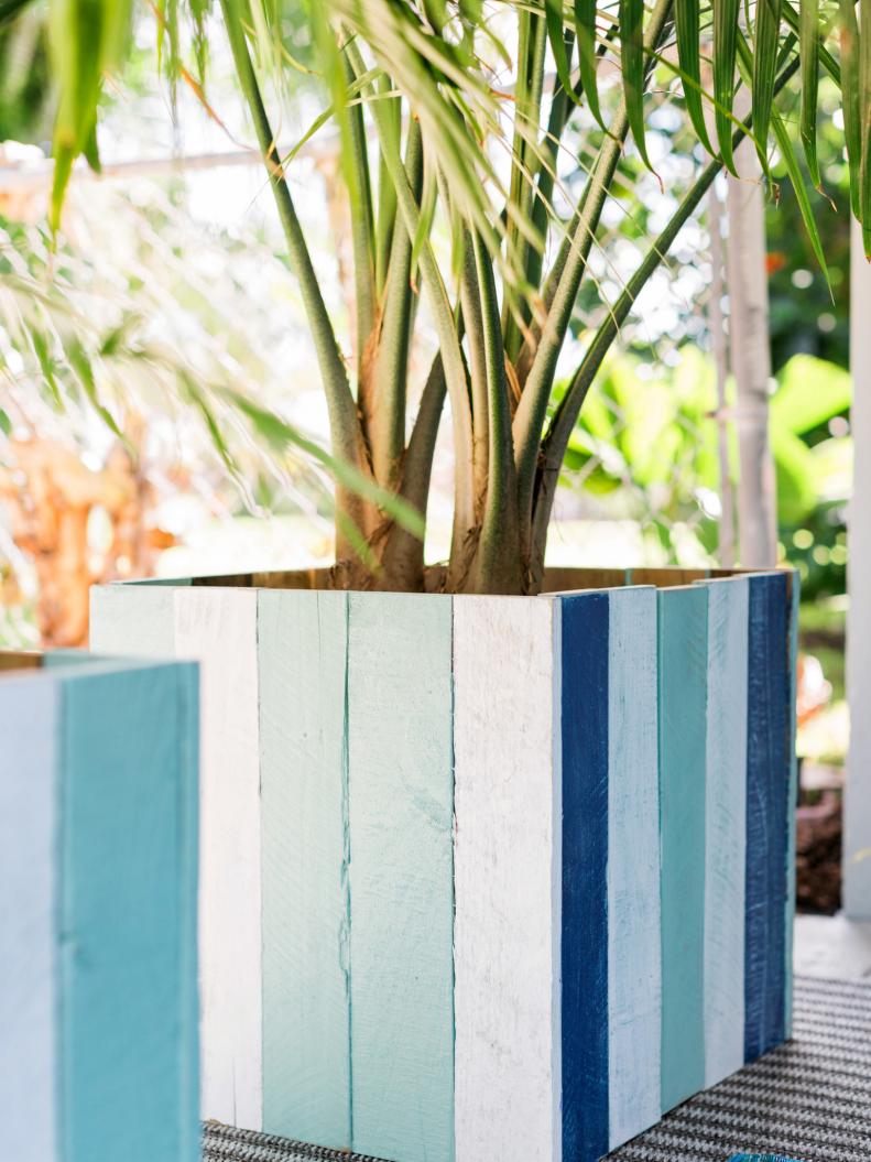 COLORFUL PLANTERS
To keep your outdoor space feeling layered and vibrant, try sneaking color in through practical items like planters and vessels. These up cycled pallet wood planters add touches of white, aqua and indigo to the corners of the room along with the graphic, linear pattern created by the vertically installed planks.