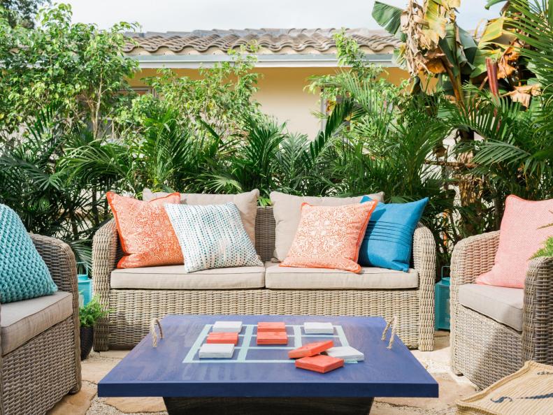 TROPICAL
With a lush Floridian backdrop of green palms and sunshine yellow exterior walls, this outdoor space was dressed in beachy shades of coral, navy and aqua simply with easily removable accents and accessories. Anytime you're working with colors in the blue, yellow and coral family, it's best described as tropical.