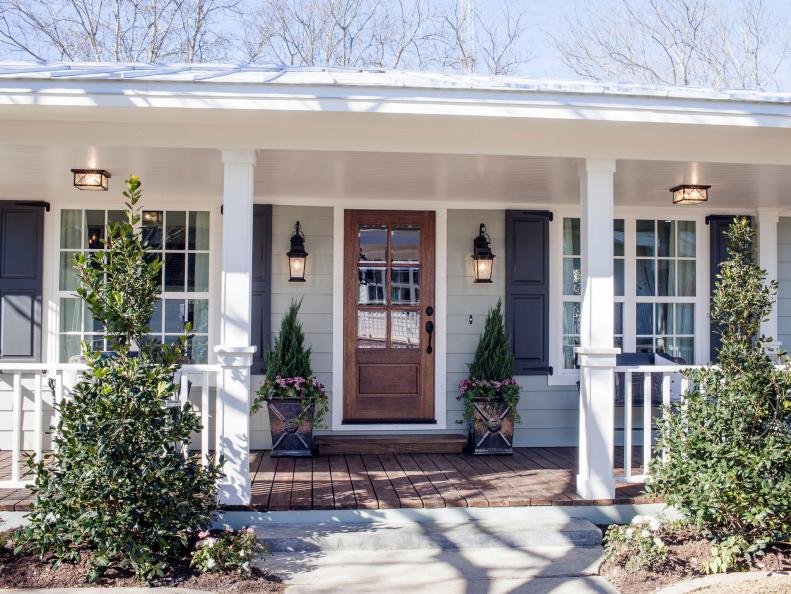 The exterior of the Ward's newly remodeled house has a new front door, black shutters, light fixtures and landscaping, as seen on Fixer Upper. (After)